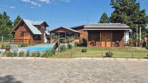 Un complejo turístico con cabañas de madera, piscina y camino pavimentado.