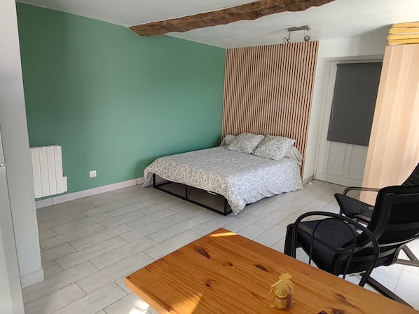 Um quarto com uma cama, uma mesa de madeira e uma cadeira.