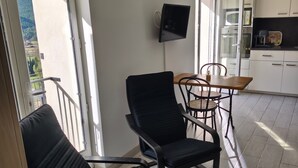Un balcón con dos sillas, una mesa y un televisor en la pared.