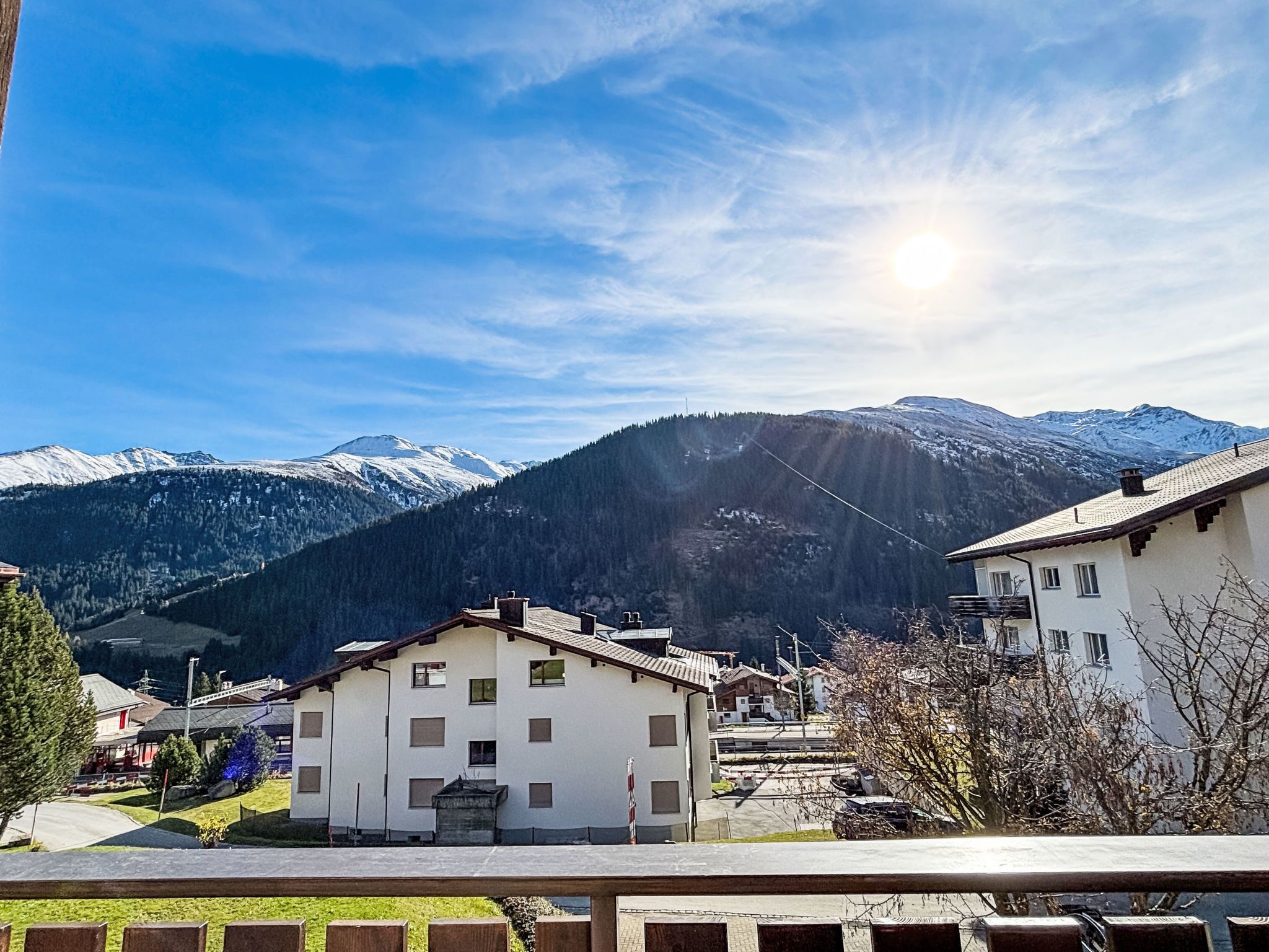 Ein Wohngebiet mit Häusern, blauem Himmel und schneebedeckten Bergen im Hintergrund.