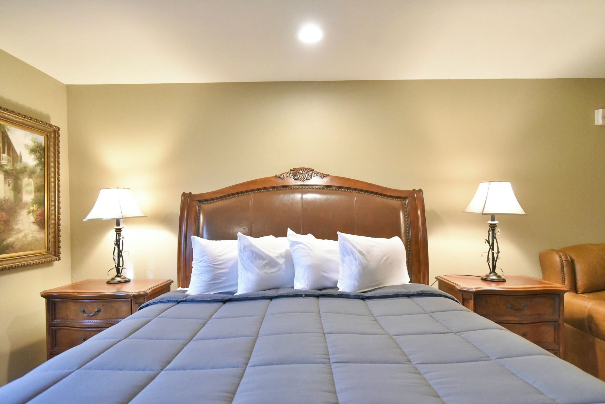 A hotel room with a large bed, two bedside tables, and a painting on the wall.