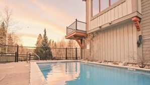 A swimming pool with a wooden deck, a metal fence, and a building with a balcony. - Marina Park Mountain View Townhome: Heart of Frisco (Frisco)