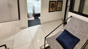 A bedroom with a bed, a wardrobe, a bathroom with a toilet and sink, and a hallway with framed pictures. - premier luxury apartment (Accra)