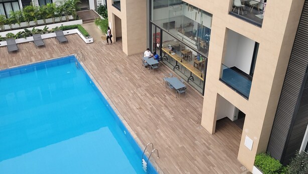 A modern building with a rooftop pool, outdoor seating, and a glass-walled dining area. - premier luxury apartment (Accra)