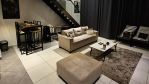 A modern living room with a sofa, coffee table, and a staircase leading to an upper level. - premier luxury apartment (Accra)
