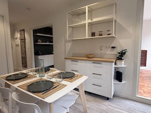 Een moderne keuken met witte kastjes, een houten aanrecht en een eethoek gedekt met borden, glazen en bestek.