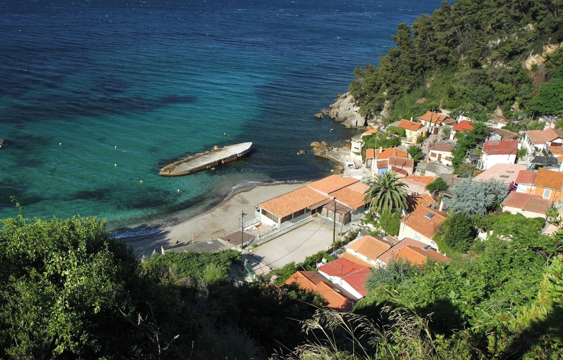 A coastal town with buildings, a dock, and clear blue waters.