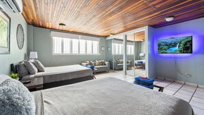 Et moderne hotelværelse med træloft, en stor seng, en sofa, et fjernsyn og udsigt til et vandfald.