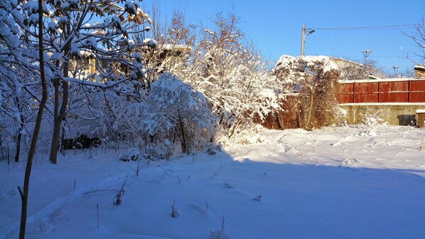 Paesaggio innevato con alberi spogli e un edificio rosso.