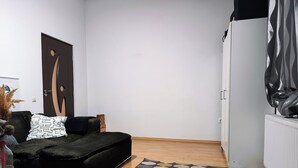 Een moderne woonkamer met een zwarte bank, een getextureerd vloerkleed en een houten vloer.