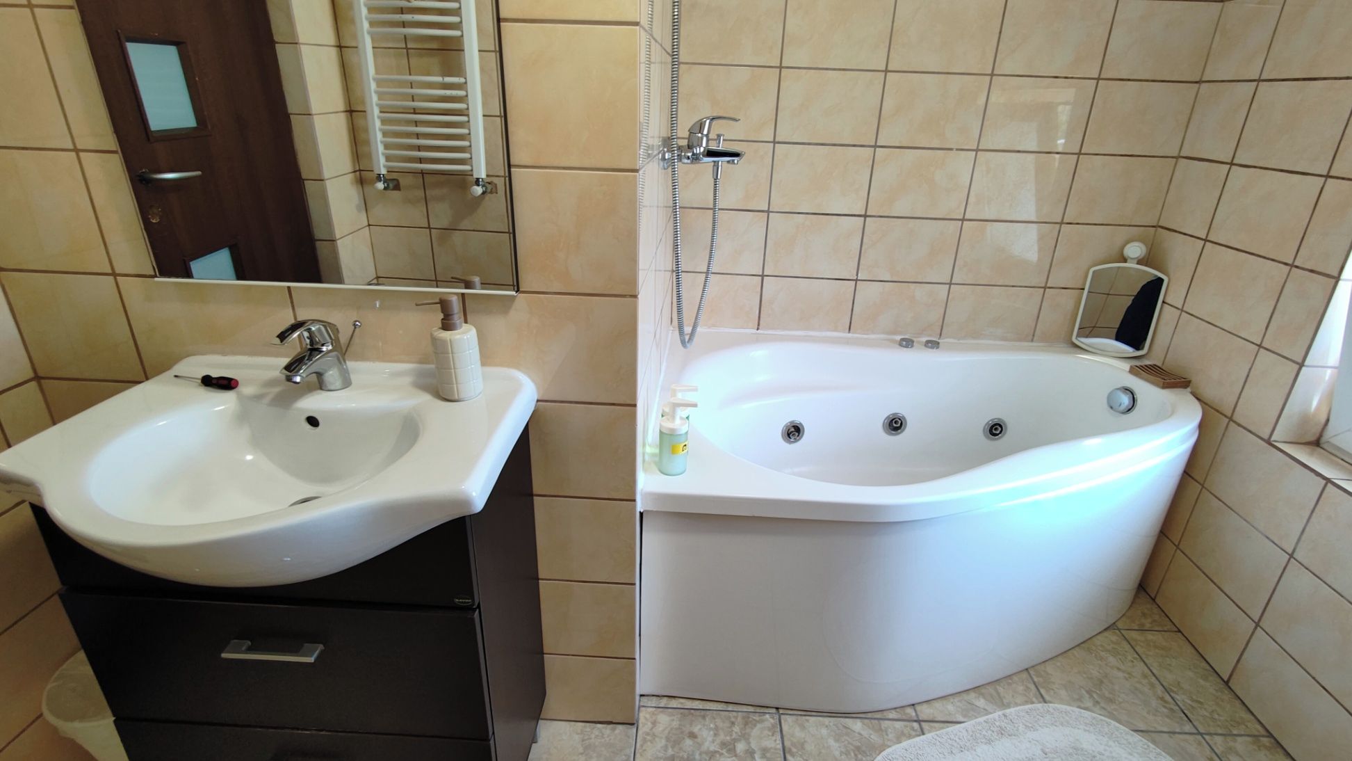 Un bagno con lavandino, specchio, portasciuga, doccia e vasca da bagno.