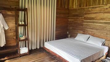 A wooden-paneled room with a bed, a shelf with toiletries, and a curtain.