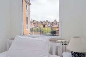 A room with a bed, a window with a view of buildings, and a lamp. - Gorgeous penthouse with terrace near Piazza Navona (Roma)