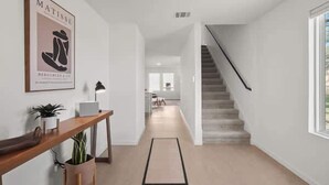 Een modern interieur met een trap, een bureau met een laptop en een lijstwerk aan de muur.