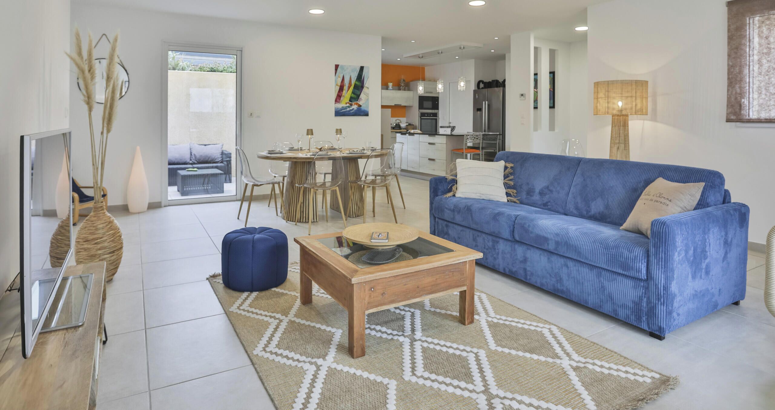 Un salon moderne avec un canapé bleu, une table basse en bois et un coin repas avec des chaises.