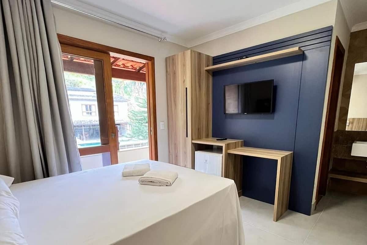 Ett modernt hotellrum med en stor säng, en tv som är monterad på väggen, ett skrivbord och utsikt över omgivningarna.