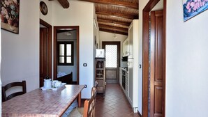 A narrow hallway with a tiled floor, wooden ceiling beams, and a kitchen area with white cabinets and a microwave. - Detached cottage with spaiggia within walking distance, sea d mountain view! (Santa Maria Navarrese)