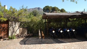 A stone-paved courtyard with a covered seating area and parked motorcycles. - Detached cottage with spaiggia within walking distance, sea d mountain view! (Santa Maria Navarrese)