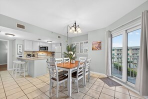 A modern kitchen with white cabinets, a wooden island, and a dining area with white chairs.