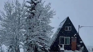 A snow-covered house with a steep roof, surrounded by trees and a snowy landscape. - Serene 2-bedroom A-Frame in Jefferson perfect for Hot Tub + Views + Stargazing (Jefferson)
