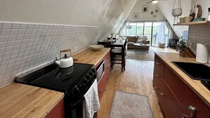 Une cuisine équipée d ’une cuisinière, d’un évier et de plans de travail en bois. On y trouve également un coin repas avec une table et des chaises.