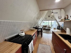 Cocina con estufa, pileta y encimeras de madera. Cuenta con una zona de comedor con mesa y sillas.