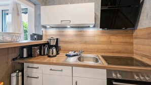 Una cocina moderna con horno empotrado, microondas y cafetera.