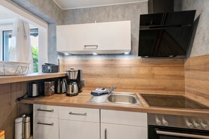 Una cocina moderna con horno empotrado, microondas y cafetera.