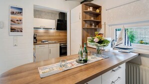 Una cocina moderna con armarios de madera, horno empotrado y ventana con vistas a zonas verdes.