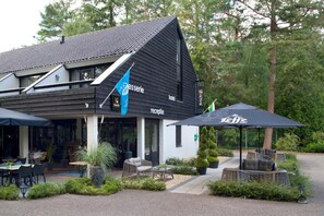 A hotel with a black and white exterior, a reception area with outdoor seating, and a sign for 'Leffe'. - Spacious Ground-floor Apartment in Lochem (Lochem)