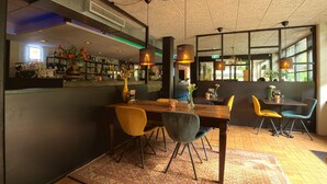 A modern dining area with a wooden table, colorful chairs, and hanging pendant lights. - Spacious Ground-floor Apartment in Lochem (Lochem)