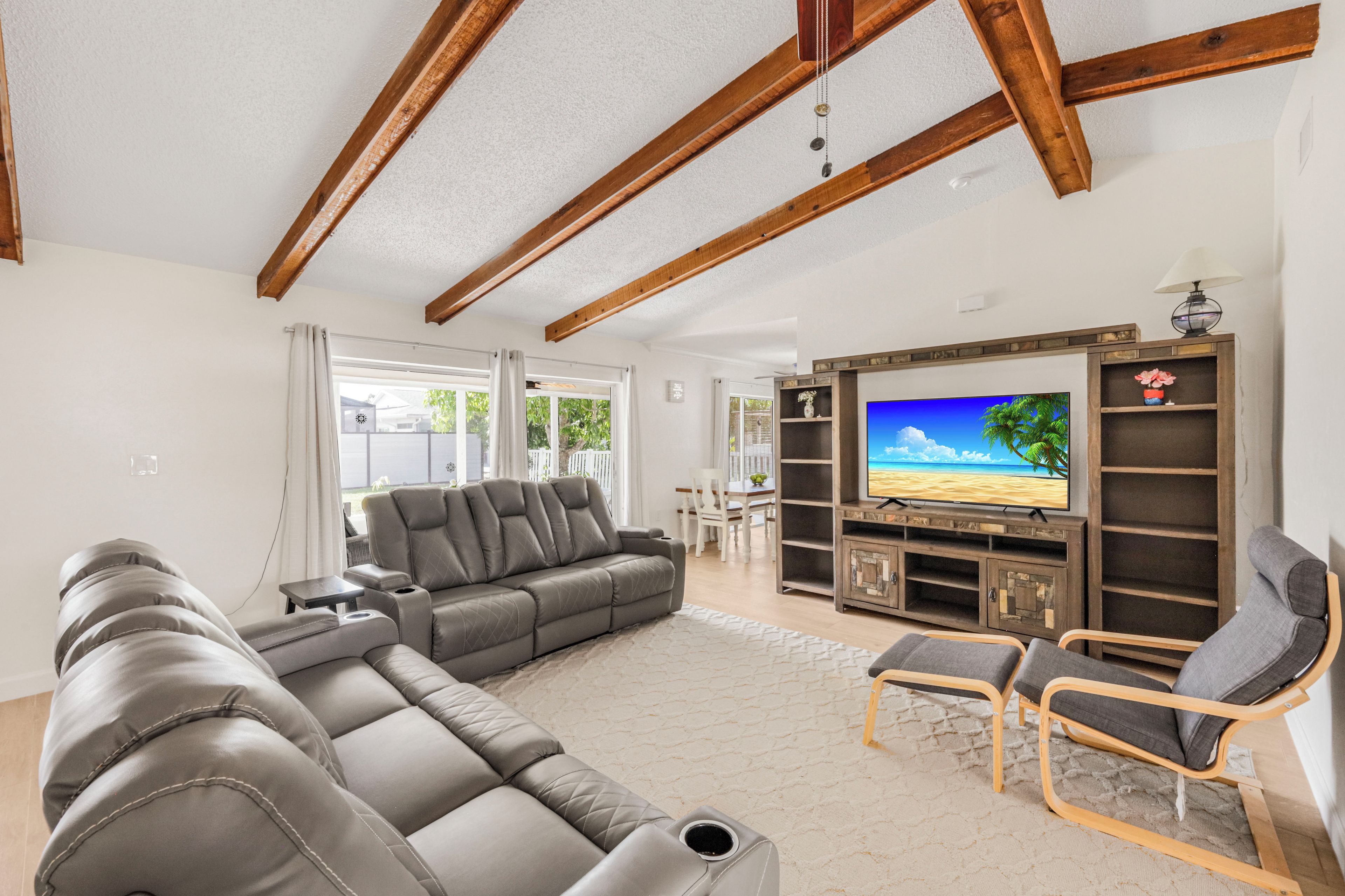 A modern living room with a sectional sofa, a recliner, and a TV on a wooden entertainment unit.