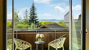 Ein Balkon mit zwei Stühlen, einem kleinen Tisch und einem Blumenstrauß.