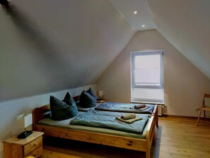 Una habitación con dos camas de madera, una ventana, una mesita y una silla.