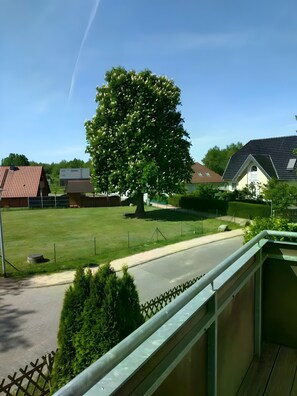 A residential area with a large tree, a road, and houses with different roof styles.