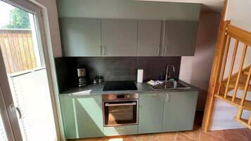A compact kitchen with a built-in oven, a coffee maker, and a sink.