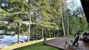 A wooden deck with a view of a lake and trees. - The Hidey-Ho on Lower Clam Lake | Secluded | Private Dock (Clam Lake)