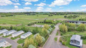 A residential area with modern houses, a golf course, and a large building with a flat roof. - Cozy Coastal Retreat 3-bedroom Lodge at (Prestonpans)