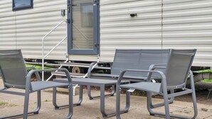A row of metal chairs and a table outside a mobile home. - Cozy Coastal Retreat 3-bedroom Lodge at (Prestonpans)