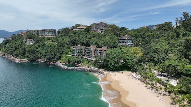 A coastal hotel with multiple buildings, a beach, and a rocky shoreline. - Porto Real Resort - Daily Rates and Seasonal Rates (Mangaratiba)