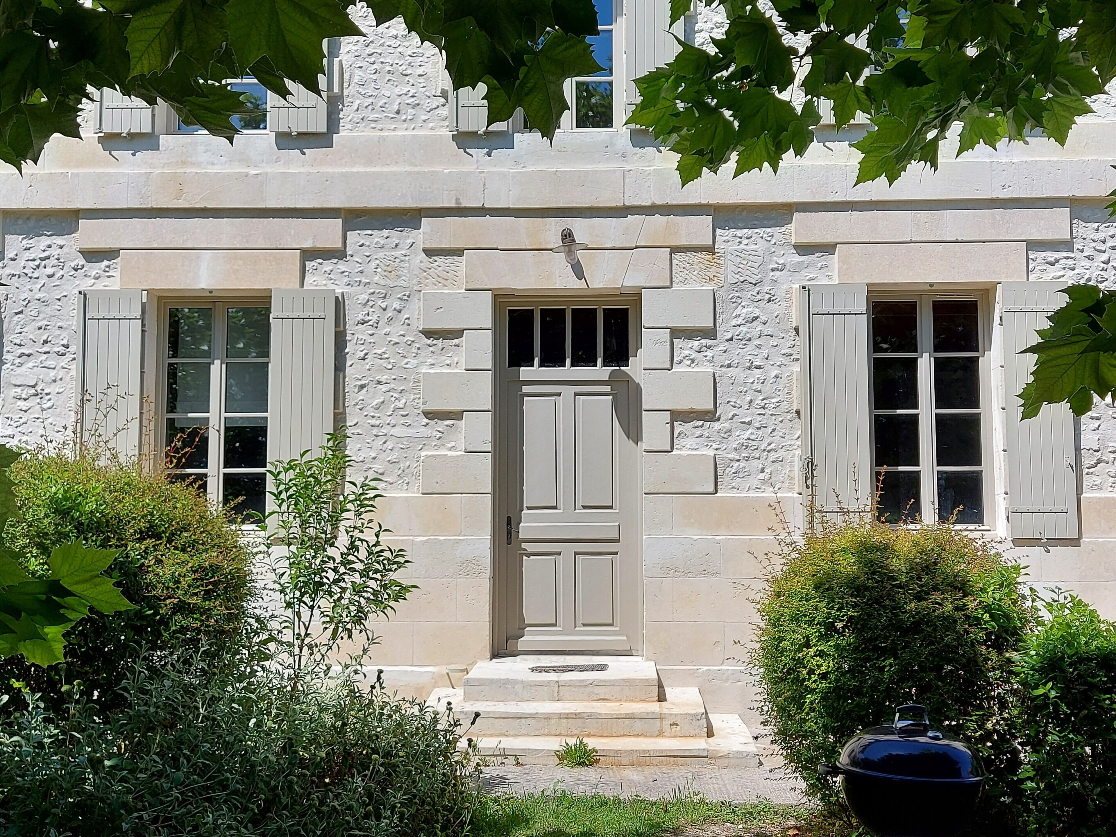 A stone building with a central door, two windows with shutters, and a small porch.
