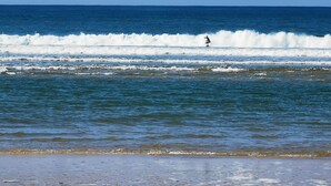 Una spiaggia con onde e una persona che fa surf.