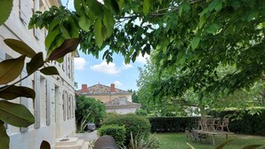 Un cortile con giardino, una struttura metallica e un edificio con tetto in tegole.