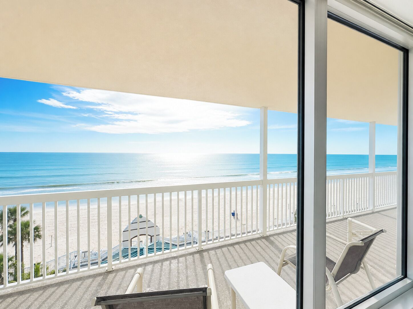 A balcony with a view of the beach and ocean.