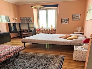 Ein Schlafzimmer mit einem Bett, einem Schreibtisch, einem Stuhl, einem kleinen Tisch und einem Fenster.
