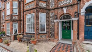 A corner townhouse with a green door, stone accents, and a checkered pavement outside. - Sea View Penthouse - Walkable to Beach & Town (Norfolk)