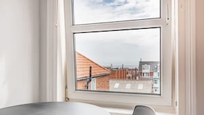 A room with a large window overlooking a cityscape, a round table, and a chair. - Sea View Penthouse - Walkable to Beach & Town (Norfolk)
