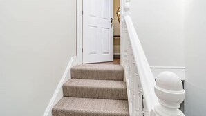 A staircase with beige carpeted steps and white balusters. - Sea View Penthouse - Walkable to Beach & Town (Norfolk)