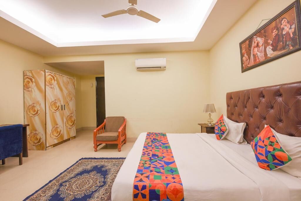 Une chambre à coucher avec un lit, un ventilateur de plafond, un climatiseur, une chaise, un canapé bleu et un tapis à motifs.