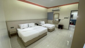 A hotel room with two beds, a bedside table with a phone, a small cabinet, and a mirror. - Rahet Al-Kharj Serviced Apartments (Al Kharj)